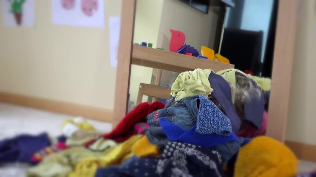girl with curly blond hair lying near mirror and colorful clothes falling down