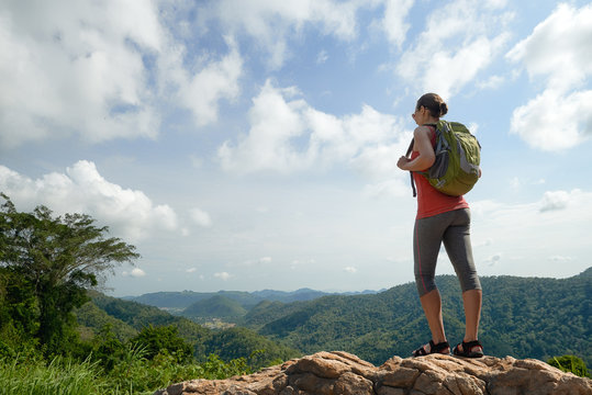 Traveller woman with backpack enjoying  view to valley on background mountains