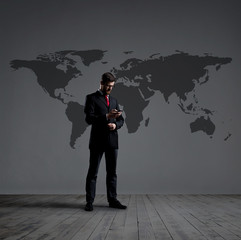 Businessman standing with smartphone. World map background. Business, globalization, concept.