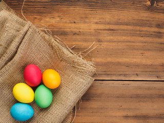 Easter eggs on old brown wood and burlap background. Top view, horizontal. Mock up for your greetings card or poster. Russian and Ukrainian, orthodox, slavic traditional Easter, rural background.