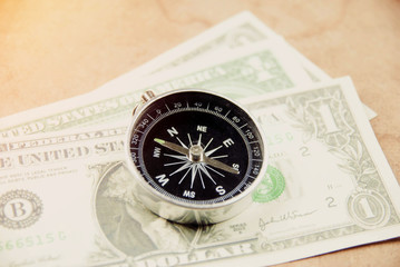 Magnetic compass with pocket money on work table, ready for traveling.
