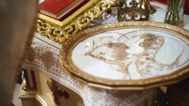 The close-up portrait of the priest hallowing the embroidered icon druing the wedding in church.