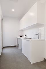 Crisp white laundry with overhead cupboards and chrome tapware