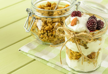 Healthy breakfast ingredients. Homemade granola with yoghurt in open glass jar. The food is rich in useful carbohydrates, vitamins and nutrients that are essential for health.  Copy space.