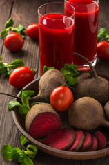 Healthy eating, dieting and vegetarian concept - glass juges of beet-tomato juice with vegetables on dark wooden background . Detox and healthy diet . 