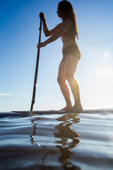 Female paddleboarding at sunrise