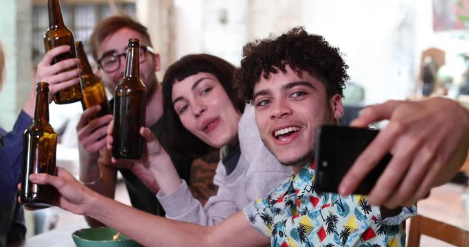 Group of friends posing for a group selfie with beer bottles
