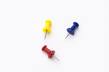 Three colored push pins on white background