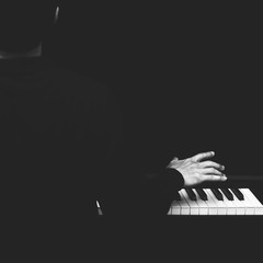 back of male asian musician playing piano, black and white