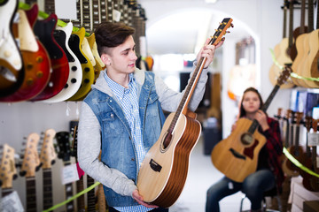 Teenage choosing best acoustic guitar