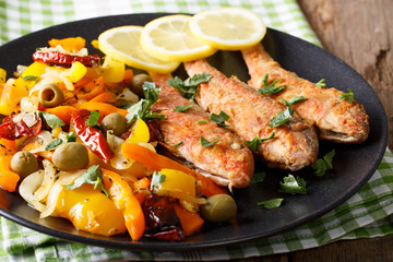 Roasted red mullet with stewed vegetables, lemon and greens close-up. Horizontal