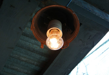 Old grunge lamp hanging on rough wooden ceiling.