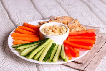 hummus served in a bowl with fresh vegetable sticks and whole grain crackers