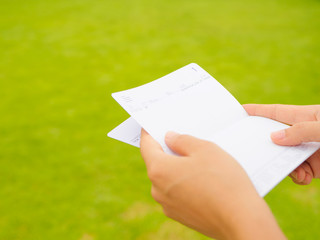 hands holding saving account passbook, book bank on the green grass background