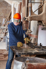 Alter Schreiner an Bandsäge in Schreinerei