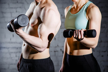 Fototapeta na wymiar Strong young couple working out with dumbbells. Shot in studio on a white background.