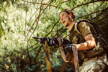 Man in military uniform with machine gun in the woods. military, war and people concept