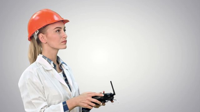 Female construction worker operating a crane using remote control on white background.