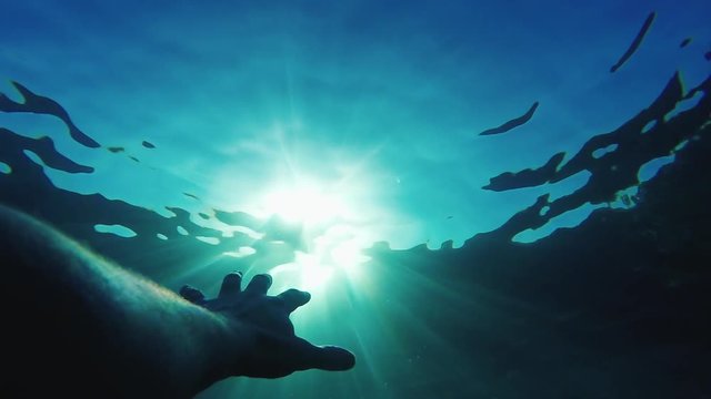 The man's hand reaches out to the sun under the water. Concept - hope, salvation, waiting for help.