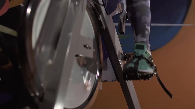 Close-up of bike simulator and strong female legs turning the pedals