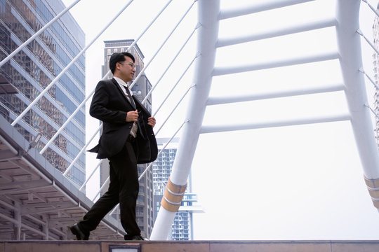 Confident businessman going down and walking on stairs and modern office building background
