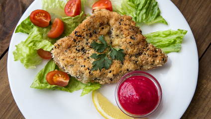 closeup of Homemade Breaded Schnitzel with salad and berry sauce
