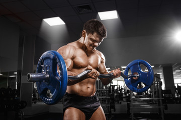 Fototapeta na wymiar Athlete muscular bodybuilder in the gym training with bar