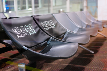 Priority seat. Bench in the terminal of airport. Empty airport terminal waiting area with chairs.