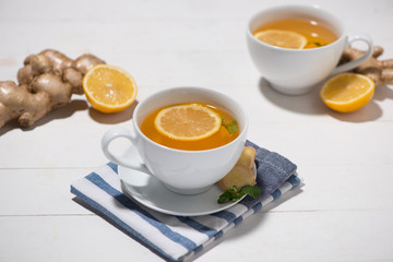 Cup of Ginger Tea with Lemon and Honey on a White Wooden Background.