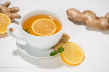 Cup of Ginger Tea with Lemon and Honey on a White Wooden Background.