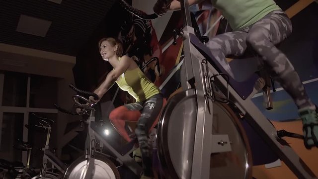 Young women working out on stationary bikes at night