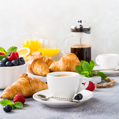 White cups of coffee and croissants on light gray background, selective focus. Healthy breakfast concept with copy space.