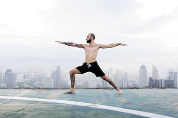 Naklejka premium Man Practice Yoga Rooftop Concept