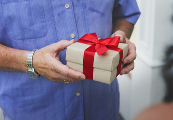 Guy holding a box of present with red bow