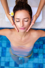 Beauty and health. Beautiful young woman getting facial massage in spa pool.