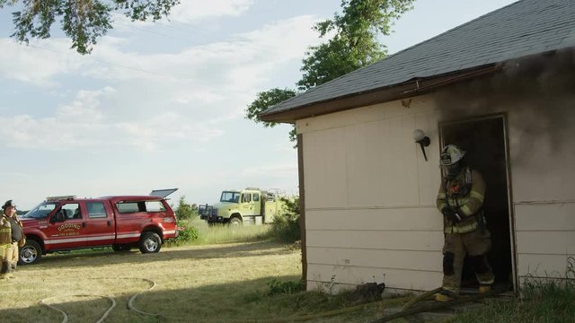 Fireman exits smoking door way from house on fire