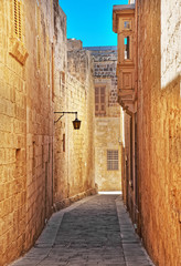 Narrow street with lantern and balcony in Mdina old town