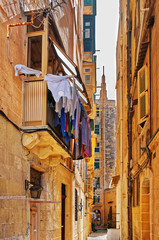Fototapeta na wymiar Old street with traditional houses and balconies in Valletta