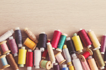 Colored thread spools on the wooden table. Sewing works. Handmade.