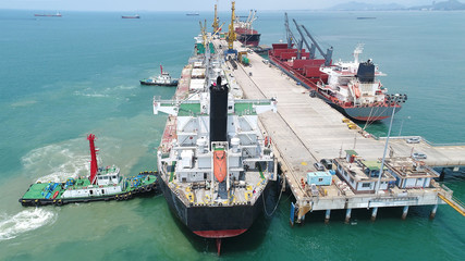 Naklejka premium ship ocean vessel in berhing along side the jetty terminal of port pushing by the tug boats in safety cirscumstance