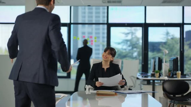  Happy female business manager talking to employee in corporate city office.