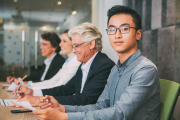 Confident Asian manager sitting at meeting