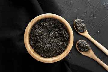 black caviar in wooden bowl on black  background