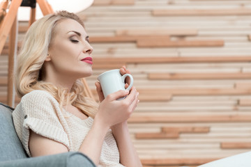 Smells good. Portrait of a charming female relaxing at home enjoying aroma of coffee.