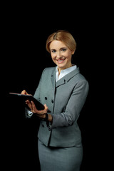 Beautiful blonde businesswoman using digital tablet and smiling at camera