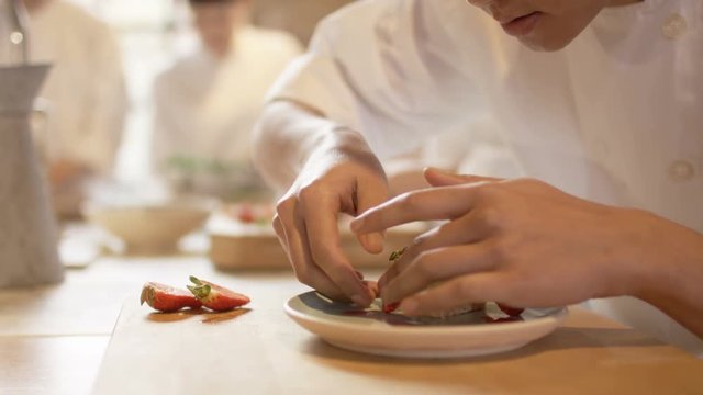  Young chef in professional kitchen gives finishing touches to dessert