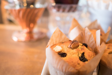 golden brown cupcake topped with raisin and cashew nut, wrapped with paper cup, on wooden brown table