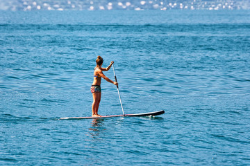 Fototapeta na wymiar Girl standing on standup paddle surfing in Geneva Lake Montreux in Switzerland