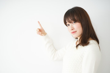 笑顔で指をさす日本人の若い女性