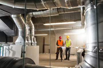 Workers making final touches to HVAC system. HVAC system stands for heating, ventilation and air conditioning technology. Team work, HVAC, indoor environmental comfort concept photo. - obrazy, fototapety, plakaty